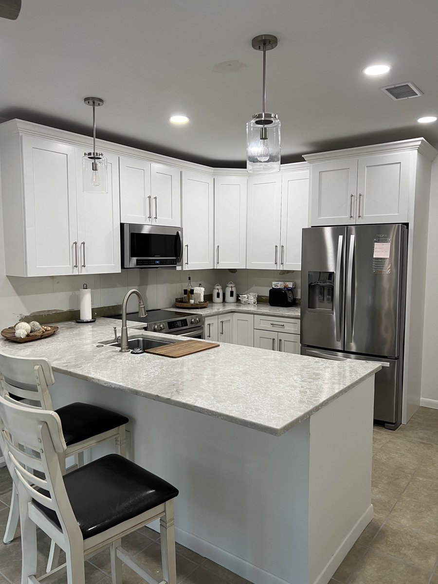 Kitchen remodel by KM — white shaker cabinets, quartz island, and stainless appliances